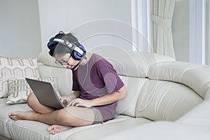 Asian teen boy using a laptop on the sofa