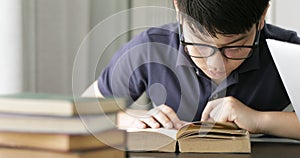 Asian teen boy waring eyeglass and used laptop computer at home, cute boy doing your homework with serious face.