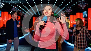 Asian teen with friends dancing and singing at karaoke club