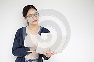 Asian teen girl with laptop computer standing on white wall thinking expression