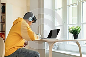 Asian teen guy taking notes during webinar studying at home