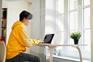 Asian Teen Guy Using Laptop Browsing Internet Learning At Home