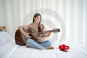Asian teen playing guitar relax in bedroom, enjoy leisure weekend at home. Stress free concept