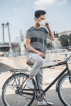 asian teen in protective mask standing with bicycle air