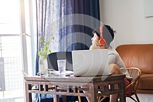 Asian teenage boy studying at home wearing headset, depressed & look out of window