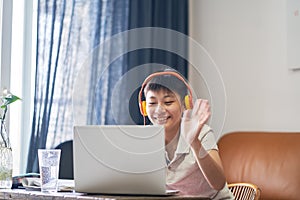 Asian teenage boy studying at home wearing headset smiling