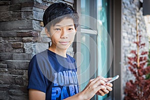 Asian teenage boy using smartphone, communication technology.