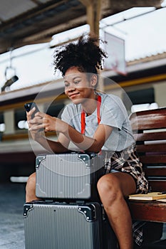 Asian teenage girl african american traveling using smartphone moblie while waiting for a train at a station.