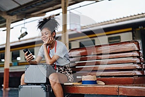 Asian teenage girl african american traveling using smartphone moblie while waiting for a train at a station.