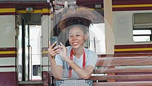 Asian teenage girl african american traveling using smartphone moblie while waiting for a train at a station.