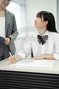 Asian teenage girl in high school uniform looking at her teacher in class