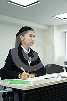 Asian teenage girl in high school uniform studying in class