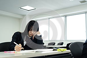 Asian teenage girl in high school uniform studying in class