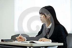 Asian teenage girl in high school uniform studying in class