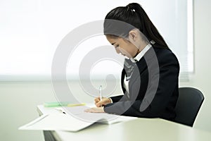 Asian teenage girl in high school uniform studying in class