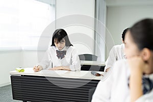 Asian teenage girl in high school uniform studying in class