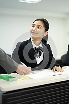 Asian teenage girl in high school uniform studying in class with teacher