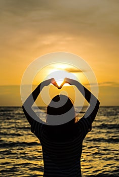 Asian Teenage girl making heart shape in sky