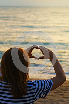 Asian Teenage girl making heart shape in sky