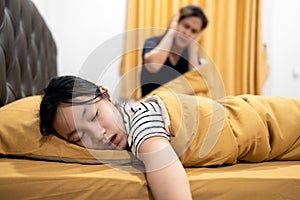 Asian teenage girl snoring loudly,open mouth,drooling on pillow,feeling tired exhausted,unhappy woman or mother covering ears with photo