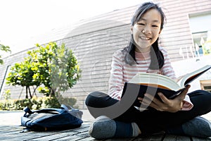 Asian teenage girl student holding a book in her hands and preparing for the exam reading book,schoolgirl reading textbook outdoor