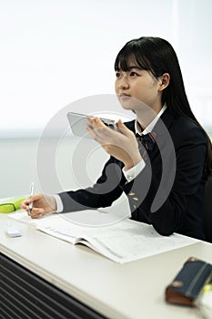 Asian teenage girl using mobile phone in class