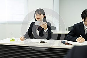 Asian teenage girl using mobile phone in class