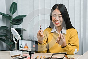 Asian teenage girls doing makeup vlogs and using a video mobile camera to record vlogs and publish them online at home