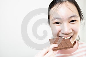 Asian teenage lady girl eating tasty chocolate bar,deliciously sweet,enjoy the natural taste,happy young woman holding chocolate photo