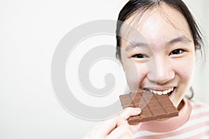 Asian teenage lady girl eating tasty chocolate bar,deliciously sweet,enjoy the natural taste,happy young woman holding chocolate