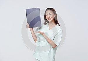 Asian teenage woman wearing a patient gown holding a policy book for assurance in life with a smiling face, insurance concept