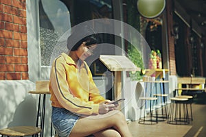 Asian teenager checking message on mobilephone at city street cafe