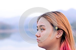 Asian teenager with colorful hair color on lake background.