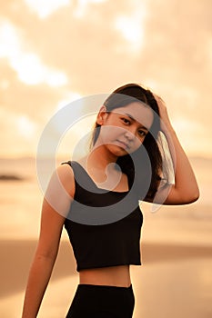 An Asian teenager with a cute face in black clothes smiles while enjoying the beautiful scenery on the beach