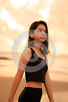 An Asian teenager with a cute face in black clothes smiles while enjoying the beautiful scenery on the beach