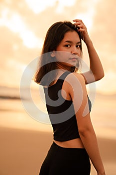 An Asian teenager with a cute face in black clothes smiles while enjoying the beautiful scenery on the beach