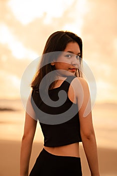 An Asian teenager with a cute face in black clothes smiles while enjoying the beautiful scenery on the beach