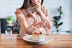 Asian teenager girl refuses to eat cheese cake. Say NO to unhealthy food, healthy eating and lose weight concept