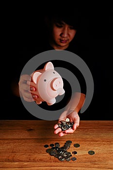 Asian teenager hold piggy bank to take coins out, saving cash coin concept investment. Management growth funding budget for wealth