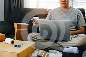 Asian teenager holds a credit card and is using a laptop computer shopping online concept