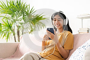 Asian teenager listen to music on smartphone with headphone enjoy. Asia woman using mobile phone happy smile  relax at home