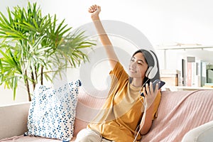 Asian teenager listening to music on smartphone with headset enjoy. raise-up hand