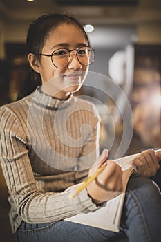 asian teenager reading a book with happiness emotion face in home living room