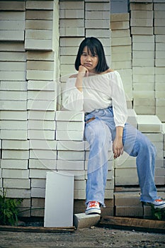 Asian teenager sitting on stack of contruction brick