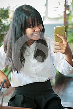 Asian teenager smiling with happiness looking to smart phone screen