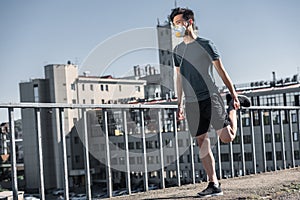 asian teenager stretching in protective mask on bridge air