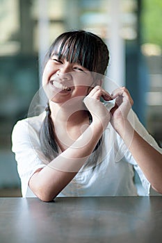 Asian teenager toothy smiling face and hand sign heart shape