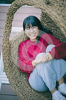 Asian teenager toothy smiling with happiness face ,relaxing on bamboo cradle