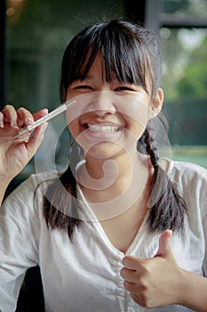 Asian teenager toothy smiling and holding body thermometer in hand