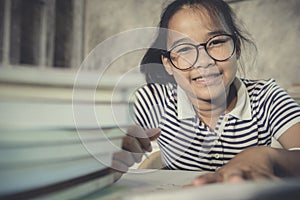 Asian teenager wearing eye glasses doing home work with stack of